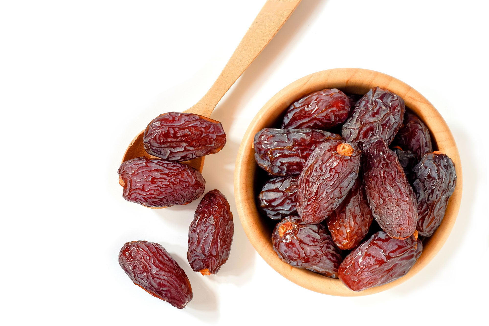 Delicious dates in bowl and on spoon next to bowl.