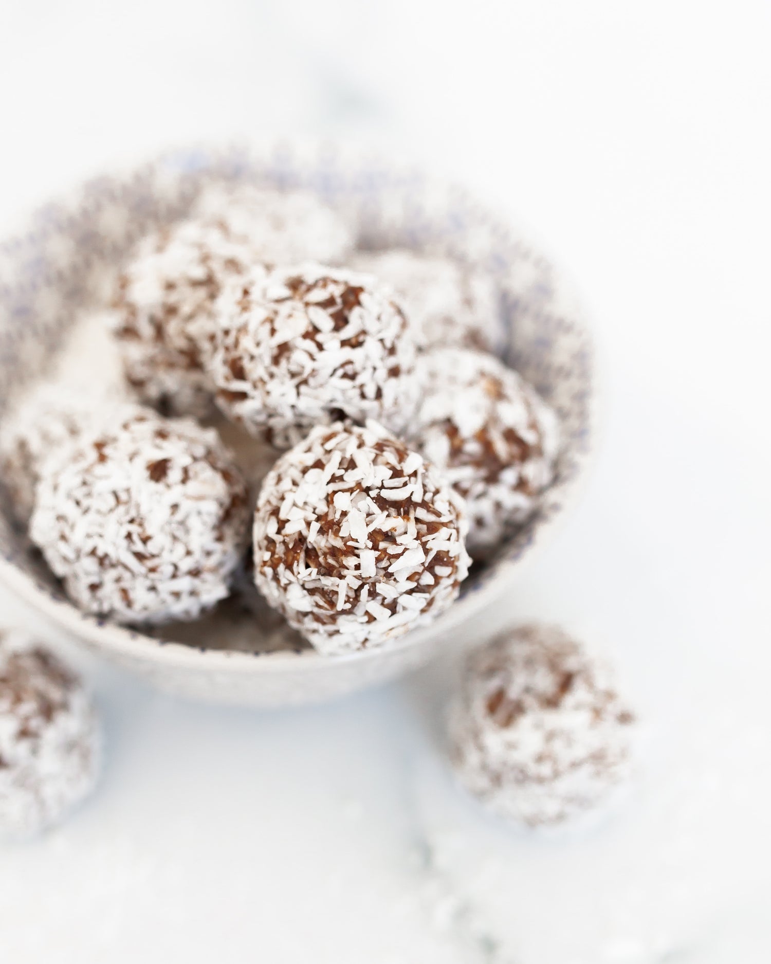 Sun Lovin' Bites rolled in coconut in white bowl on white backdrop.